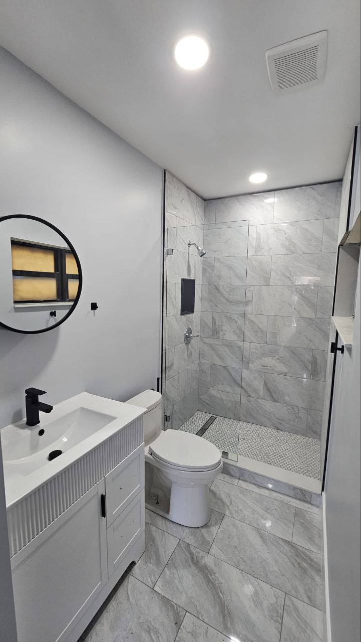 White modern vanity, matte black hardware, marble tile