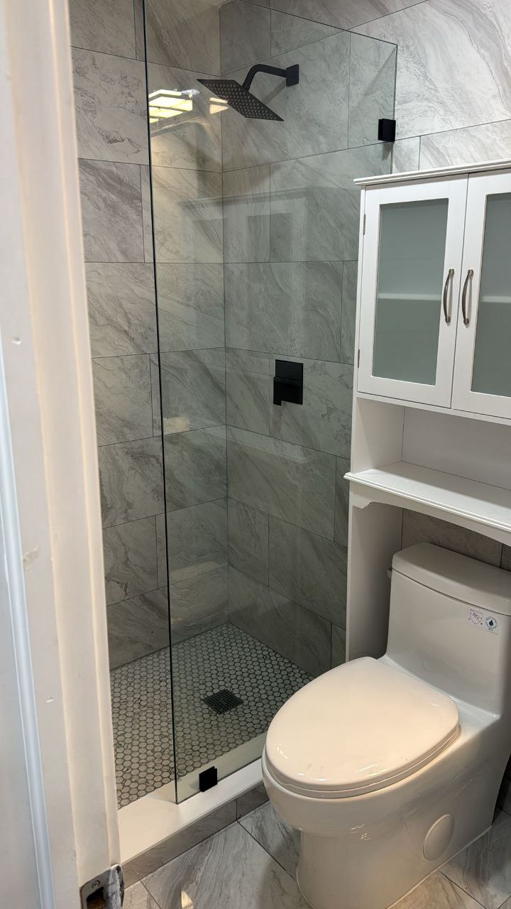 Matte black rain shower head, frameless glass, marble tile
