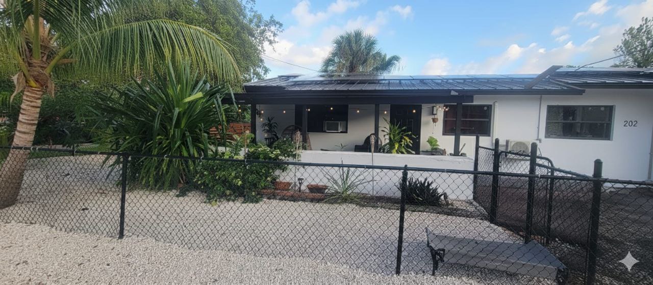 Gated entry with palm trees and string lights