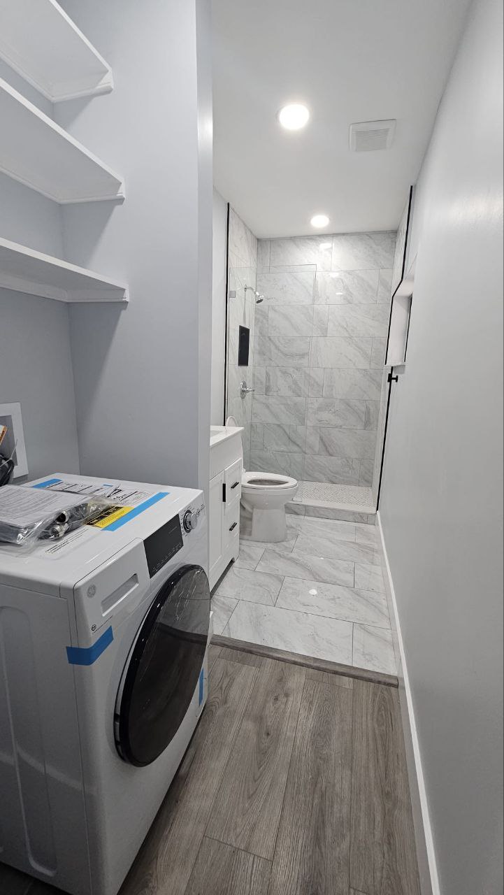 Brand new washer, marble tile bathroom behind